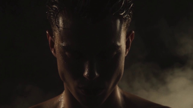 性感的运动剥离的家伙在孤立的黑色背景的水滴与烟雾视频下载