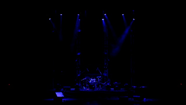 在一场音乐会上用一组鼓照亮舞台的闪烁的蓝色聚光灯视频素材