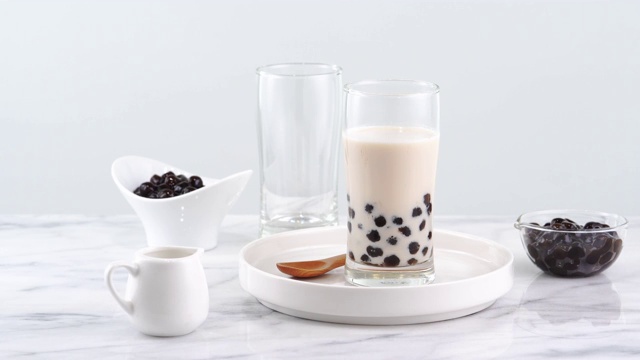 美味的珍珠奶茶在玻璃上，台湾流行的饮料在明亮的大理石桌子和白色托盘，自制的概念。4K放大拍摄视频视频下载