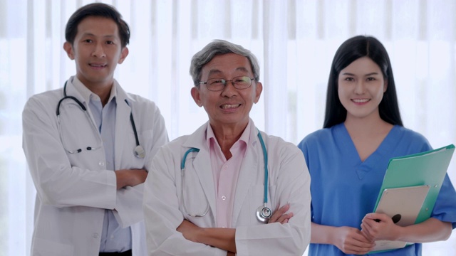 医生、护士和助理的微笑自信团队的肖像。专业医务人员工作。不同的医学科学家团队抱着双臂在医院里摆姿势，在医务室里看着摄像机。医学的概念视频素材