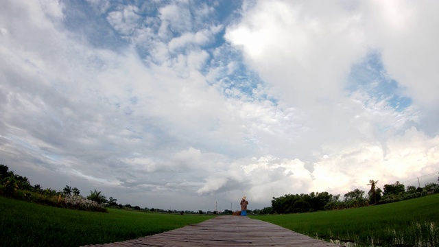 木桥和云朵的倒影在稻田的天空中快速移动。视频素材