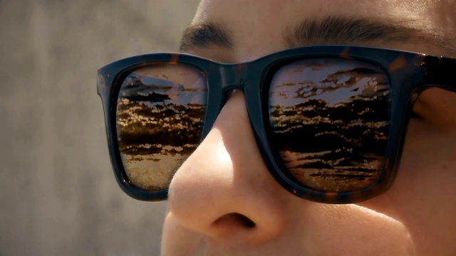 Cinemagraph -一个女人在太阳眼镜与反射波在日落视频下载