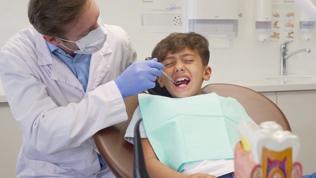 小男孩看起来很害怕，让成熟的牙医给他检查牙齿视频素材