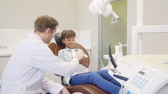 男牙医在教育小男孩关于牙齿卫生的知识视频素材