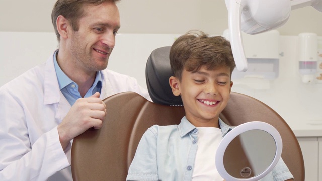 成熟的男牙医和迷人的年轻男孩一起工作视频素材