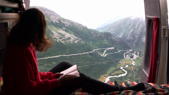 在瑞士阿尔卑斯山的福尔卡隘路附近，一名妇女从露营车里写日记视频下载