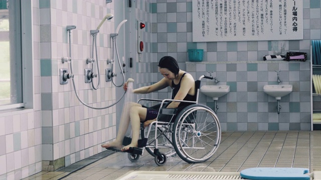 中等镜头的截瘫女运动员淋浴前或后训练的竞技游泳视频下载