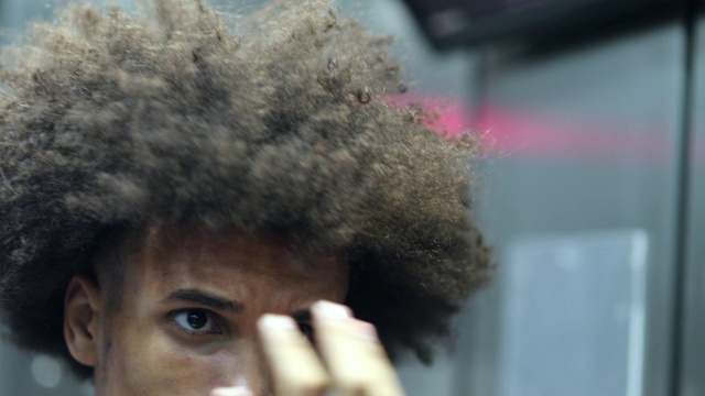 一名年轻的非洲男子梳着非洲式发型，在镜子前检查自己视频下载