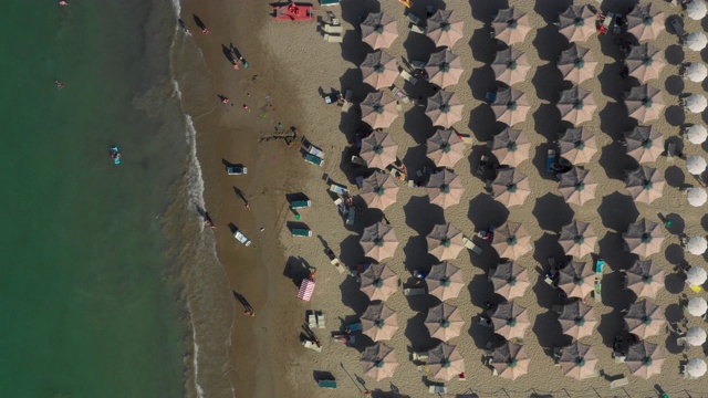 向下无人机拍摄的亚得里亚海在左边和棕色沙滩伞在右边视频素材