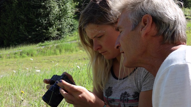 父亲和女儿在草地上练习使用照相机视频下载