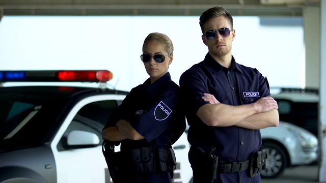 勇敢的女警察和男警察戴着墨镜，双手合十地站在汽车旁视频下载