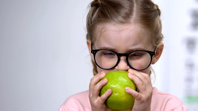 小女孩笑着戴眼镜吃绿苹果，健康营养，维生素视频素材