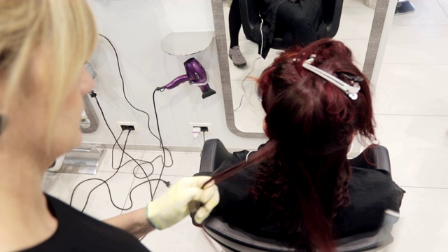 成年女子美发师为一位年轻女性顾客卷头发视频素材
