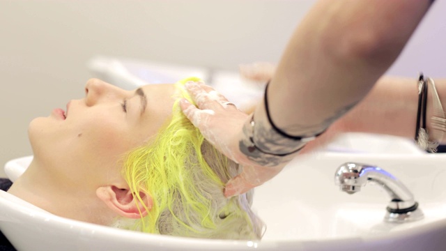 美发师用洗发水给一个金发女郎洗头视频素材