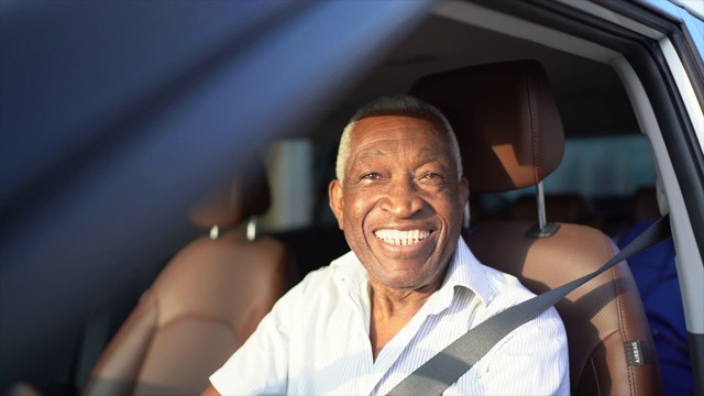 微笑的老人开着车，看着镜头视频下载