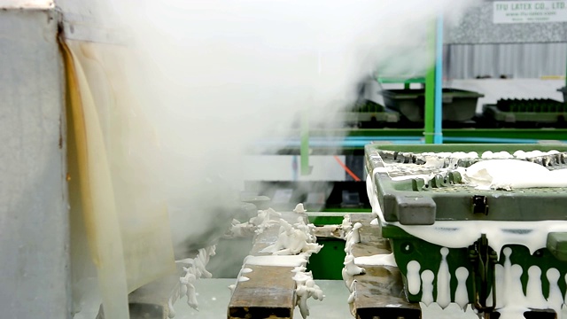 在工厂中，金属乳胶枕模具通过传送带加热蒸汽从机器中移动出来视频素材