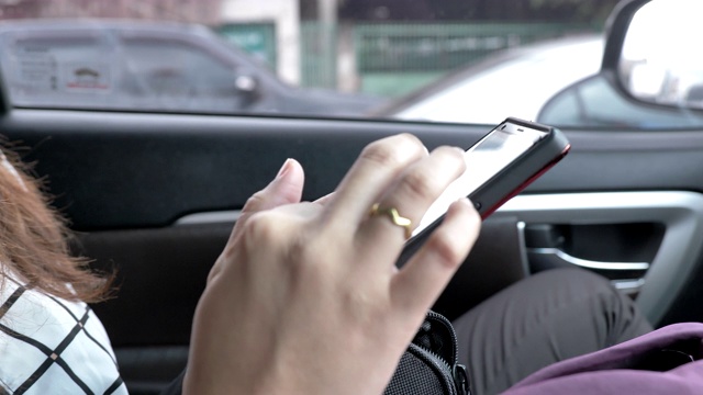 年轻的亚洲女人的场景，她坐在车里放松和使用智能手机搜索网站，女性使用智能手机的概念视频素材