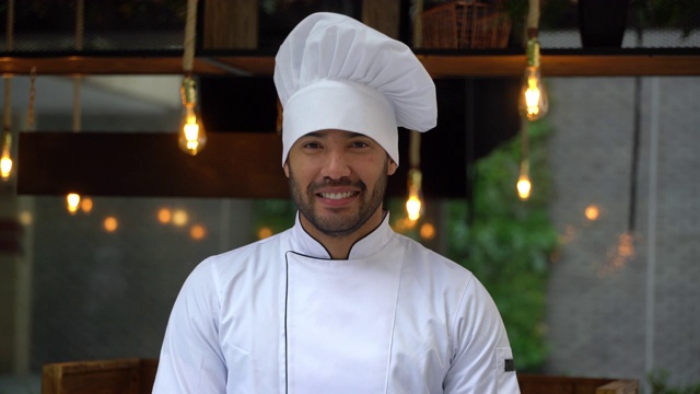 英俊的拉丁美洲厨师戴着帽子对着镜头微笑视频素材