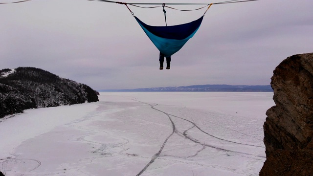 一名男子悬挂在贝加尔湖冰面上的吊床上。视频下载
