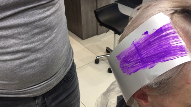 发型师将紫色染发剂涂在年轻人的头发上视频下载