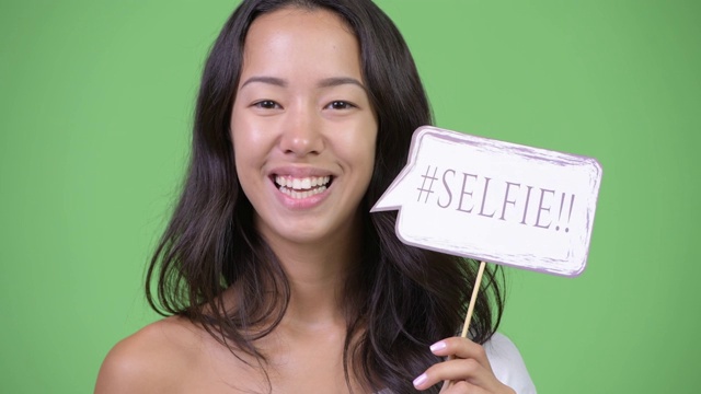 脸快乐年轻美丽的多民族女子与自拍纸标志视频下载