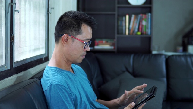 亚洲男人在客厅里用平板电脑视频素材