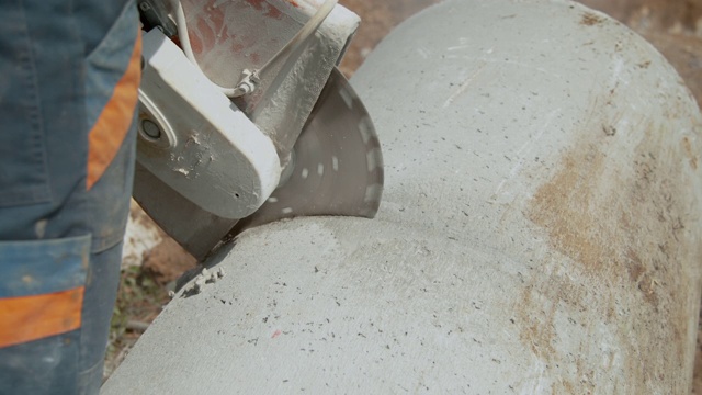 近距离观察:一名无法辨认的工人正在用圆锯切割一根大型混凝土管视频素材