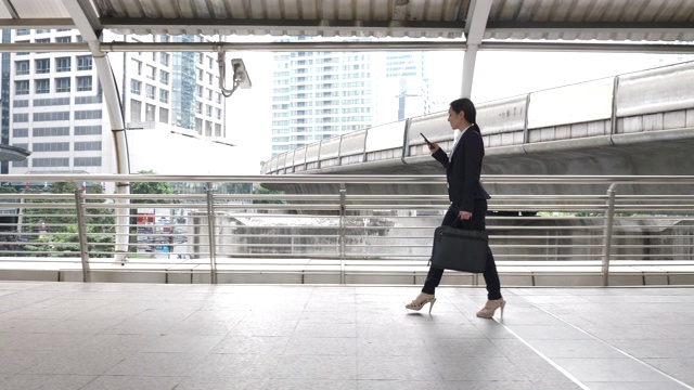 在城市里带着智能手机走路的女商人，通勤上班视频下载