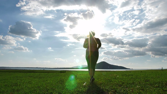 亚洲女性在傍晚的阳光下在大自然中慢跑。健身和健康生活理念。后视图的女孩在运动服跑步锻炼。慢动作视频素材