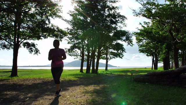 亚洲女性在傍晚的阳光下在大自然中慢跑。健身和健康生活理念。女性穿着运动服跑步锻炼。慢动作视频素材