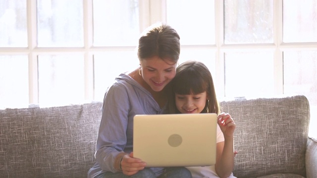 快乐的妈妈和孩子女儿享受使用笔记本电脑的乐趣视频素材