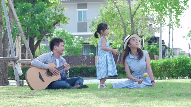 亚洲的家庭快乐。爸爸、妈妈和女儿，泰国三人在公园里以自然阳光为背景。家庭温馨，度假理念。慢动作视频下载