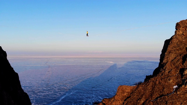 走钢索的沃克站在吊索上，在结冰的贝加尔湖的高海拔处保持平衡。视频下载