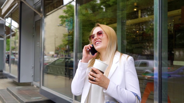 微笑的金发已婚妇女在城市街道上打电话视频素材