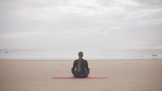 日落时分在大西洋的海滩上练习瑜伽的女人。视频素材