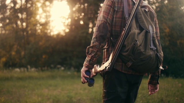 一个猎人用双筒望远镜在草地上行走的后视图(慢镜头)视频下载