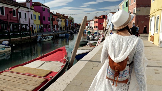 独自旅行者，年轻的女游客漫步在布拉诺岛，威尼斯，意大利。浪漫之都，典型的威尼斯风情。视频下载