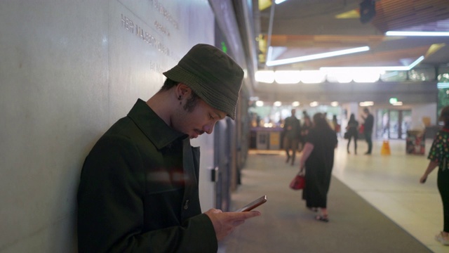 一个年轻人靠在墙上发短信视频素材