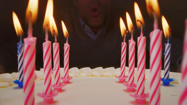 在生日蛋糕的蜡烛和一个关掉蜡烛的人之间的超级幻灯片。视频素材