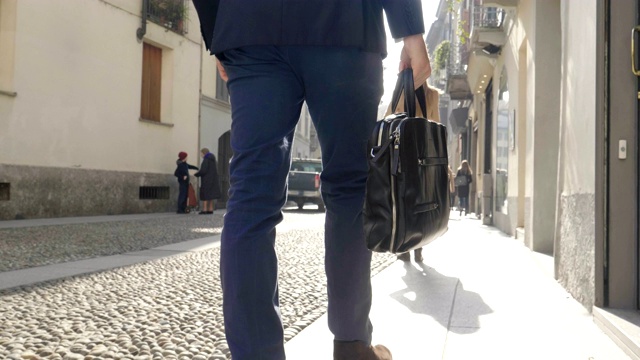 一个帅气的西装商人，带着一个公文包，在城里。视频素材