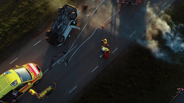 鸟瞰图:救援队的消防队员和护理人员在车祸交通事故现场工作。准备设备，急救和帮助。从燃烧的车辆中救出受伤和被困人员视频下载