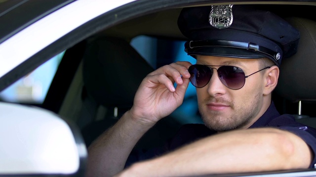 友善的警察戴着太阳镜微笑地坐在巡逻车里视频下载