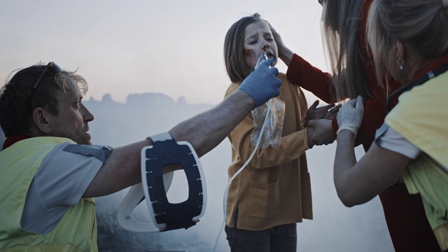 医护人员给事故中的小女孩戴上急救氧气面罩。专业人士拯救生命。烟到处都视频素材