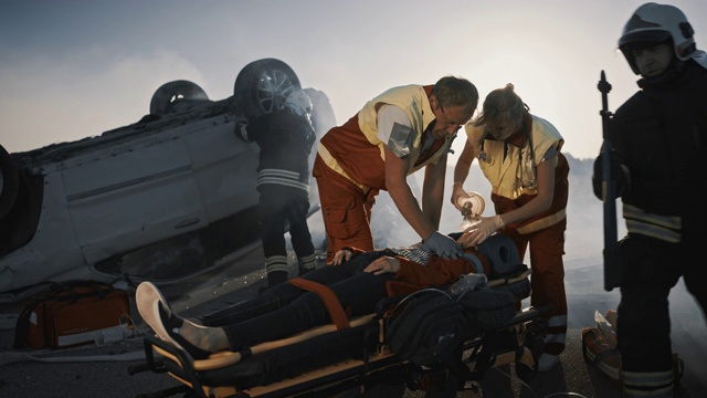 车祸现场:医护人员抢救躺在担架上的女性受害者的生命。他们敷上氧气面罩，做心肺复苏和急救视频素材