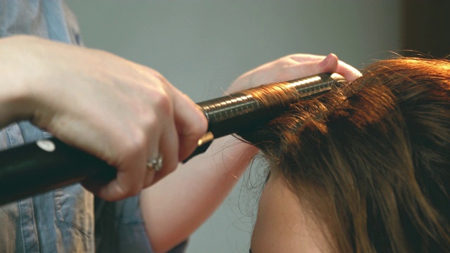 女人用发铁做漂亮的发型。卷发会很漂亮。视频下载