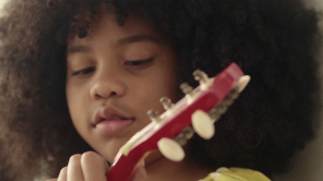 小女孩弹奏着尤克里里，唱歌视频素材