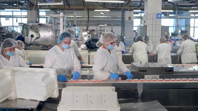 许多穿着无菌制服的妇女在一家食品厂工作视频下载