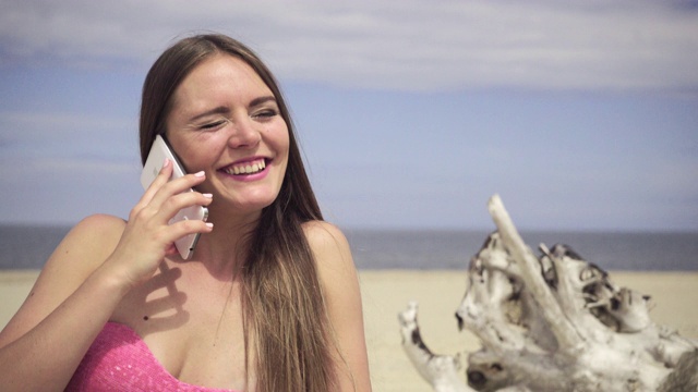 女人放松在沙滩上讲4K电话视频素材