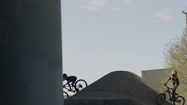 美国犹他州盐湖城天桥下骑着自行车跳山的男孩剪影的跟踪镜头视频下载