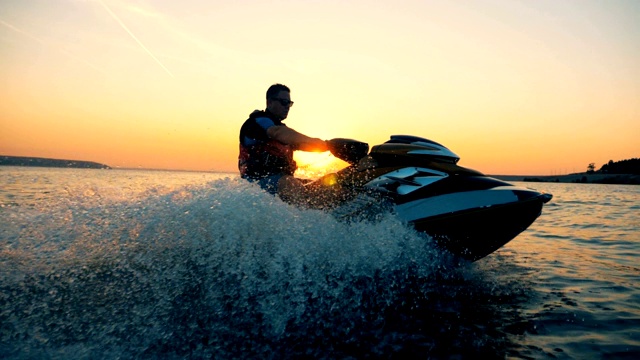 日落时分，一名男子骑着摩托艇沿着海岸线行驶视频素材